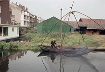 849498 Afbeelding van een visser met zijn vissersboot in de Leidsche Rijn te Utrecht, ter hoogte van houthandel De Wit.